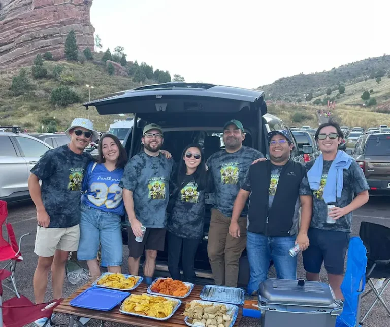 A group gathering beside an SUV before a Red Rocks concert.
