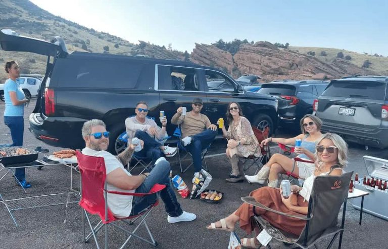 Friends enjoying a pre-concert tailgate beside their SUV at Red Rocks.