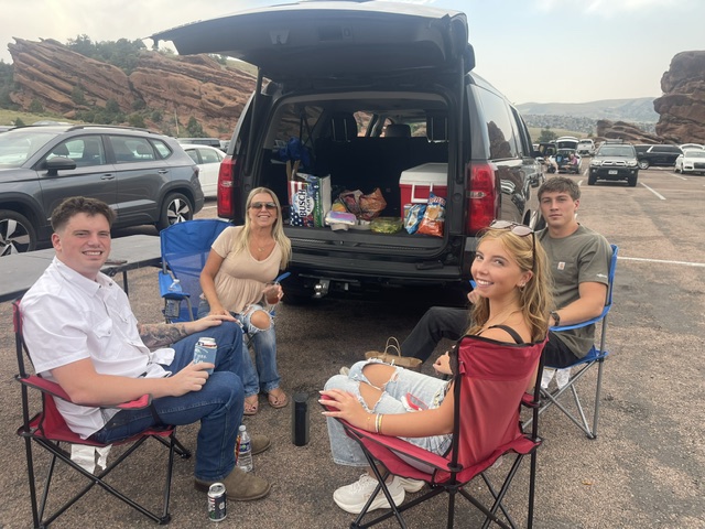 Travelers relaxing beside a black SUV at Red Rocks