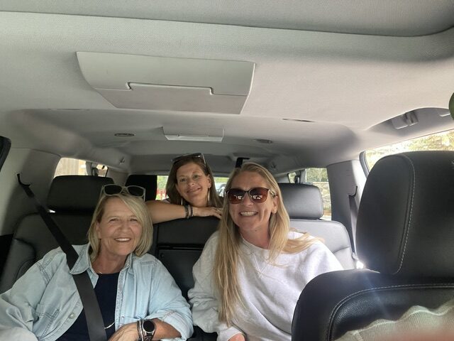 Three smiling passengers seated inside a private SUV